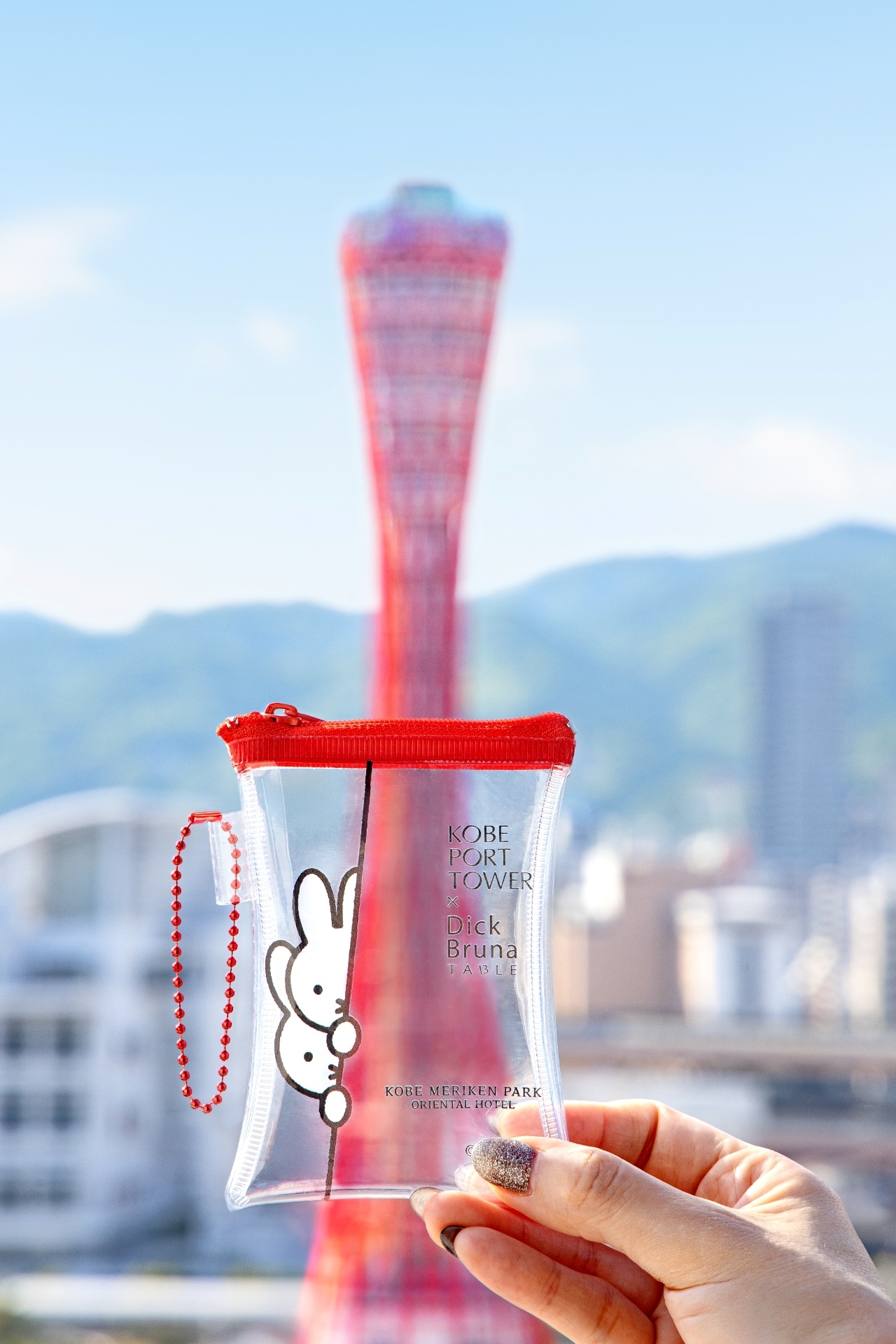 写真：神戸ポートタワーを背景にオリジナルグッズをかざす