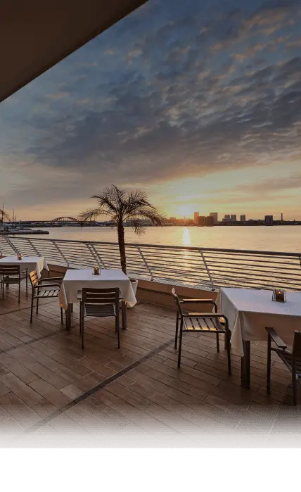 写真：レストラン「テラス＆ダイニング　オールフラッグ」のオープンテラス席と夕方の海