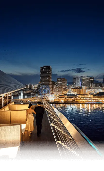 写真：バー「ビューバー」のテラス席を歩く男女の後ろ姿と西側の幻想的な夜景